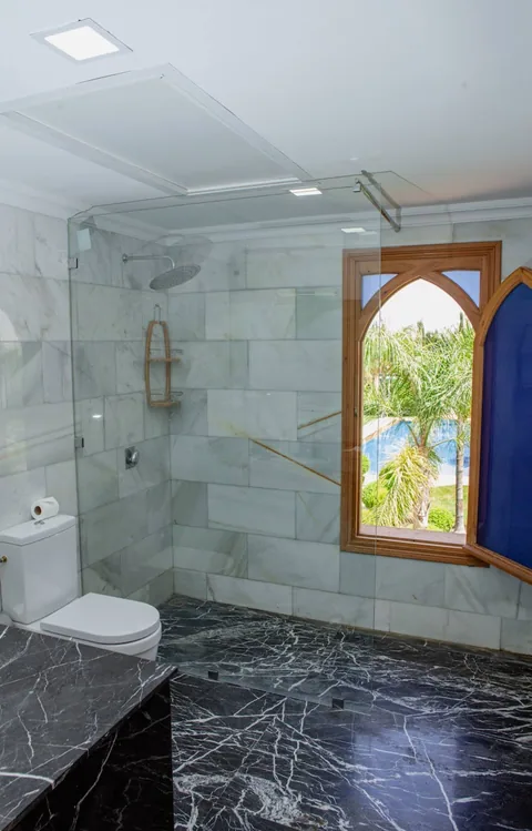 Green marble shower room with a Moorish window
