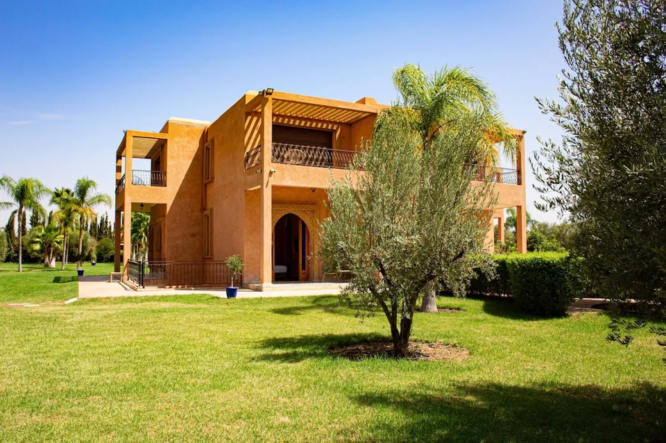 The ochre facade and corner tower of Dar Alameria rising above the lawns