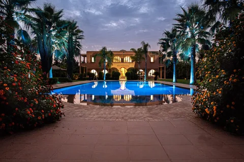 The pool and fountain terrace at dusk, lit against the Marrakech sky
