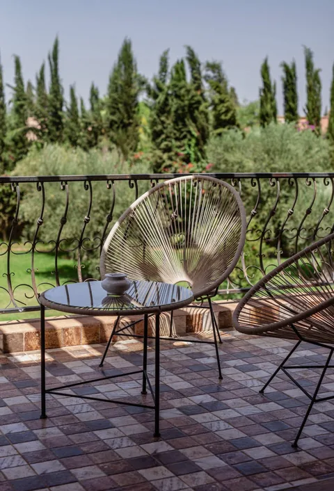 A balcony chair framed by cypress trees